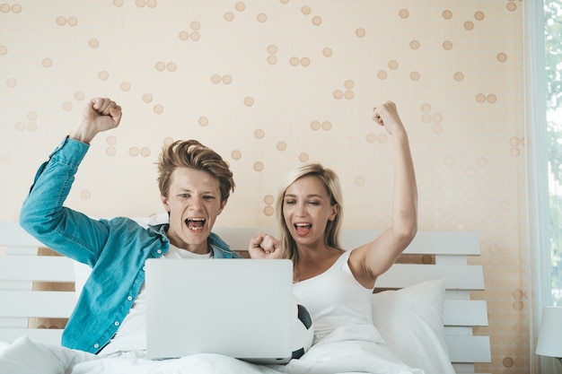 Happy couple watching soccer football on the bed