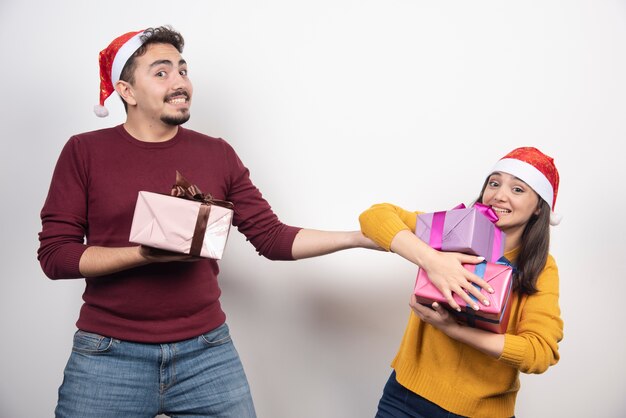 Happy couple with Christmas gifts over a white wall.