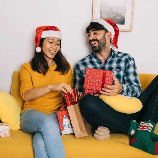 Free photo happy couple with christmas presents on couch