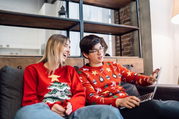 Happy couple with laptop together on sofa