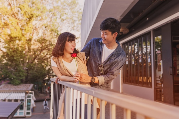 Happy couple with a rose leaning on a railing