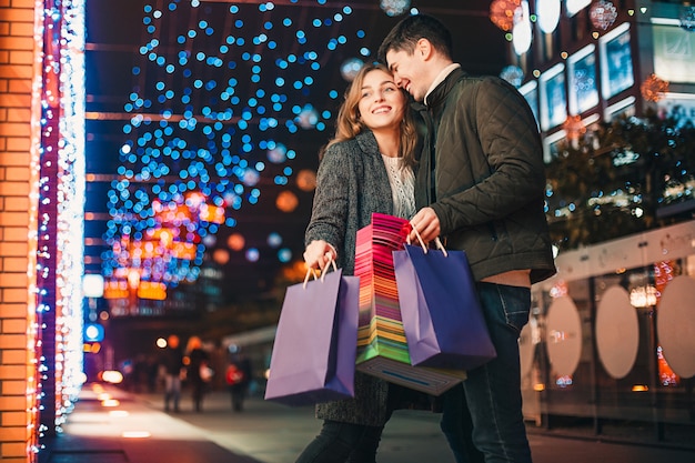 街で夜を楽しんでいる買い物袋と幸せなカップル