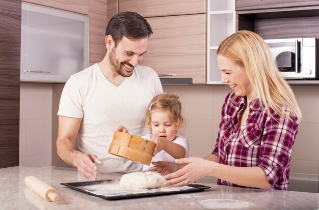 Happy couple with their little daughter baking in the kitchen