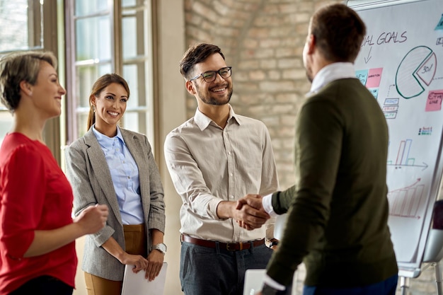 Free photo happy coworkes shaking hands after business presentation in the office