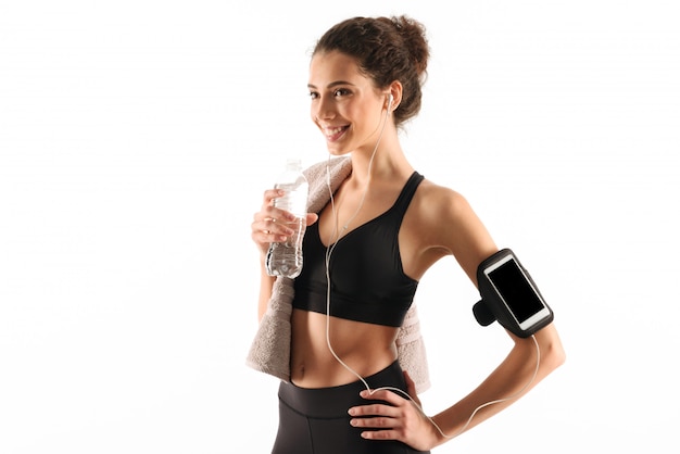 Happy curly brunette fitness woman listening music and looking away