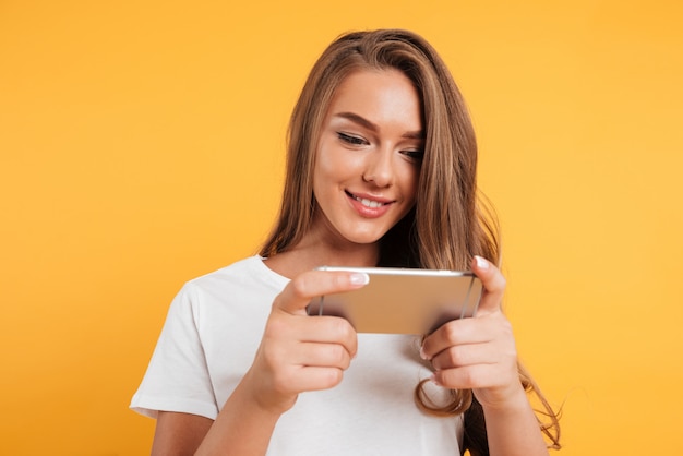 행복 한 귀여운 아름 다운 젊은 여자는 휴대 전화로 게임을