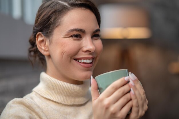 彼女のコーヒー ブレークを楽しんでいる幸せなかわいい女性
