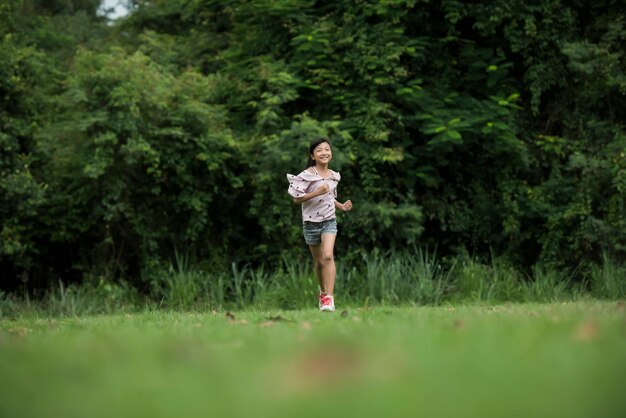 Happy cute little girl running on the grass in the park