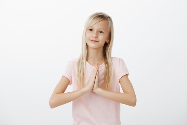 Happy cute little kid, blond woman saying thank you with hands clasped together, namaste gesture