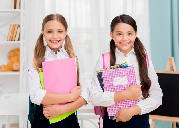 Happy cute schoolgirls smiling with copybooks