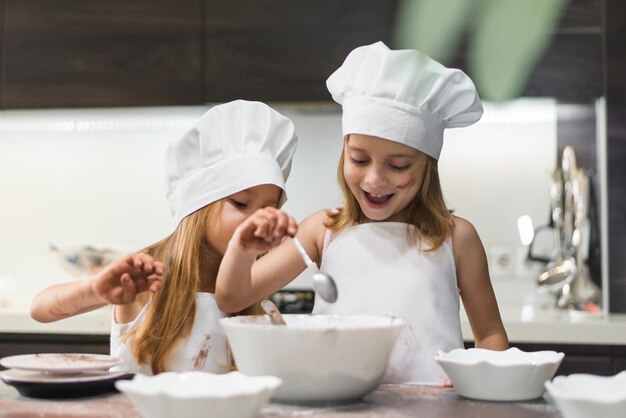 Happy cute siblings preparing food on kitchen worktop