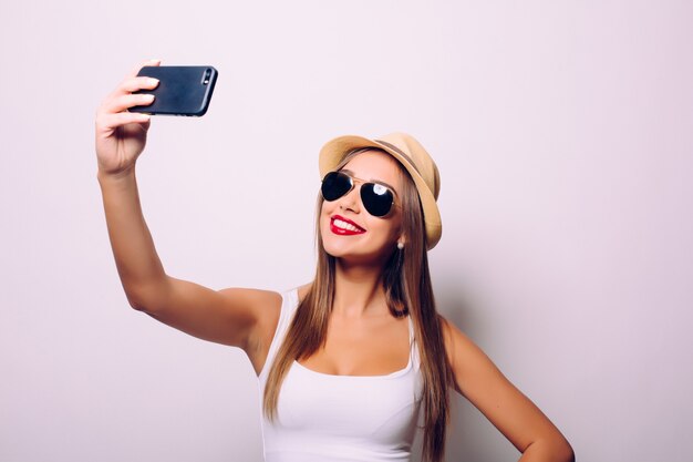 회색 벽에 고립 된 selfie를 만드는 행복 한 귀여운 여자.