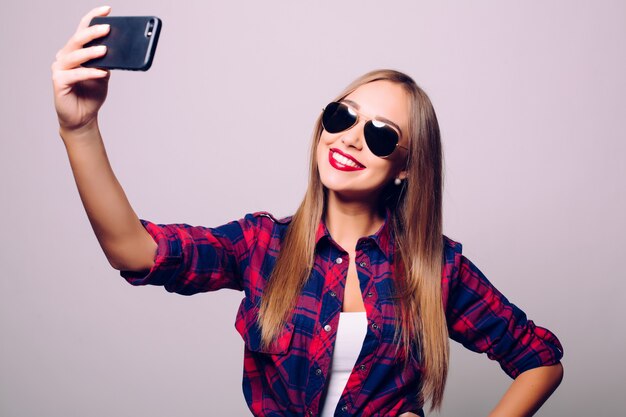 Happy cute woman making selfie isolated over gray wall.