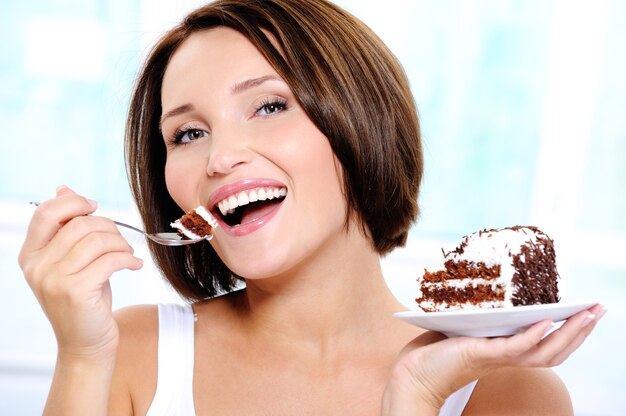 Happy  cute young woman eats a  cake