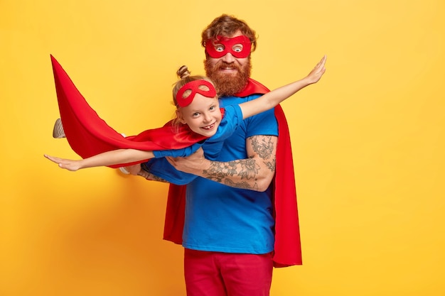 Free photo happy dad and daughter play superhero game