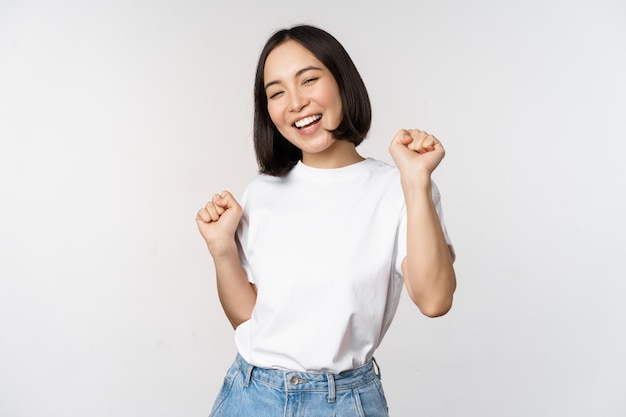 Happy dancing korean girl posing against white background wearing tshirt