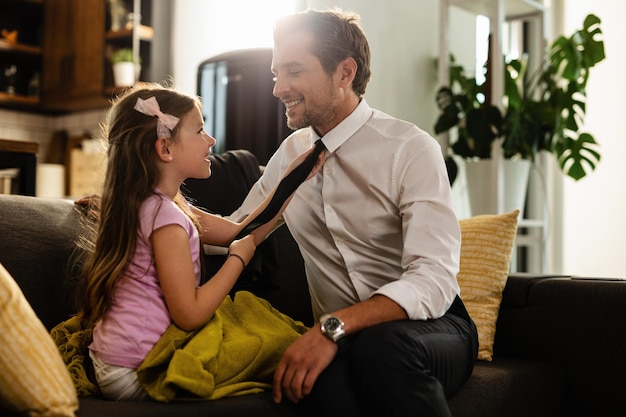 Free photo happy daughter adjusting father's necktie before he goes to work