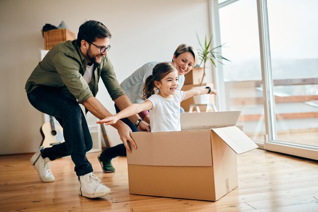 Happy daughter having fun with her parents while relocating in new apartment