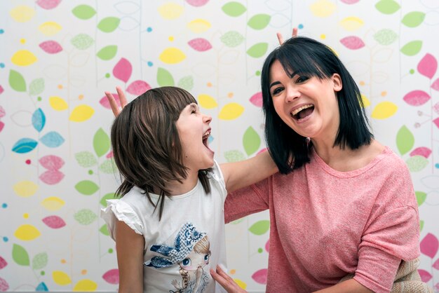 Happy daughter and mother making horns with fingers