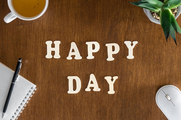 Happy day wooden letters on the office table top view