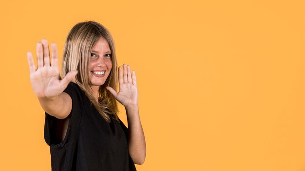 Happy deaf woman showing stop sign on plain surface