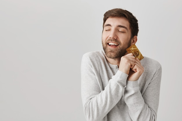 Happy delighted bearded guy hugging cold credit card