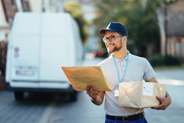 Free photo happy delivery man carrying packages while walking down the street