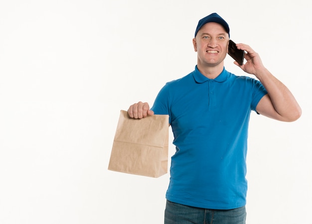 Happy delivery man holding paper bag and smartphone