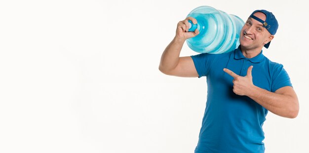 Happy delivery man pointing at water bottle and smiling