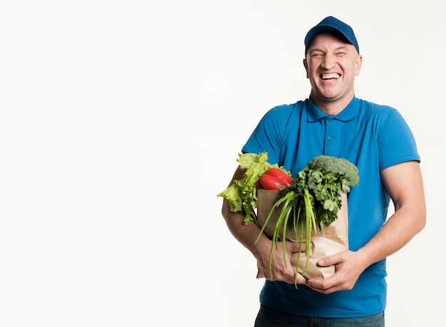 Free photo happy delivery man posing with grocery bag