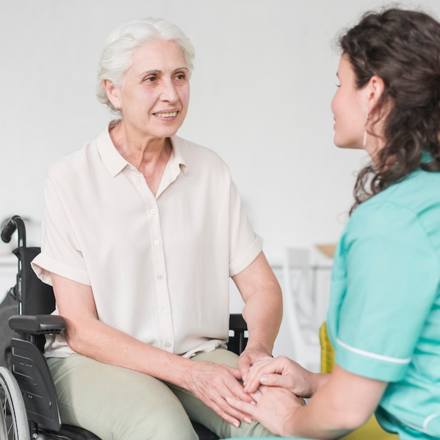 happy disabled nurse sitting on wheel chair looking at caretaker