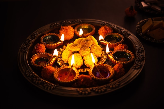 Happy diwali - flower rangoli con dolci o mithai e diya in ciotole per diwali o qualsiasi altro festival in india, messa a fuoco selettiva Foto Gratuite