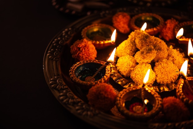Free photo happy diwali - flower rangoli with sweets or mithai and diya in bowls for diwali or any other festivals in india, selective focus