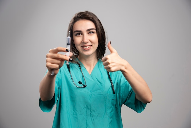 Happy doctor in uniform posing with syringe. High quality photo