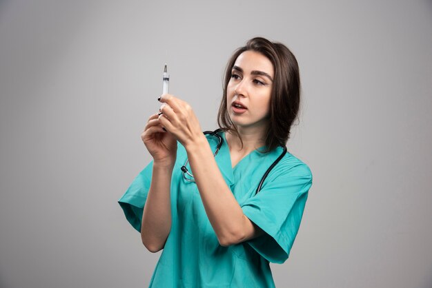 Happy doctor in uniform posing with syringe. 