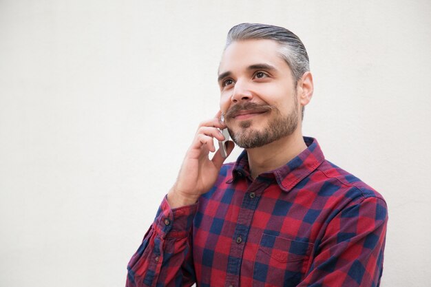 Happy dreamy man talking on phone