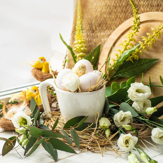 Happy Easter table. Easter egg in a nest with floral decoration near the window. Quail eggs. Happy Easter concept