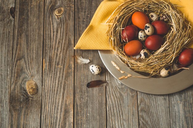 Happy Easter table. Easter eggs in a nest on a metal plate on a wooden table. Happy Easter concept