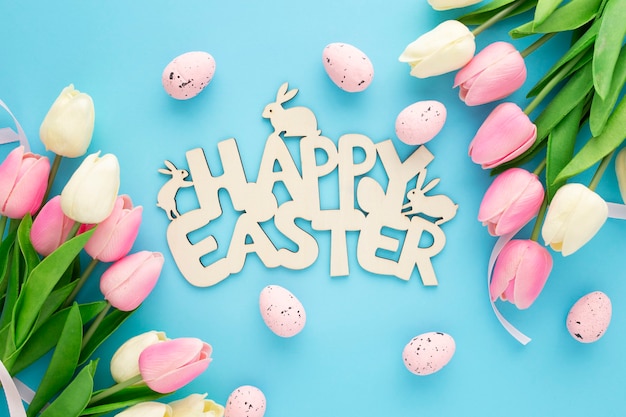 Free photo happy easter wooden sign with tulips on a blue background