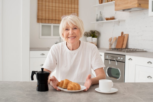 Happy elder woman sitting in the kitchen