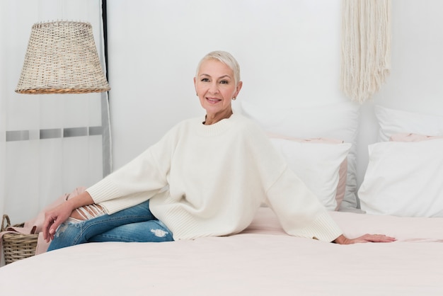 Free photo happy elderly woman posing in bed