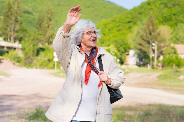 Foto gratuita felice anziana donna che cammina in campagna