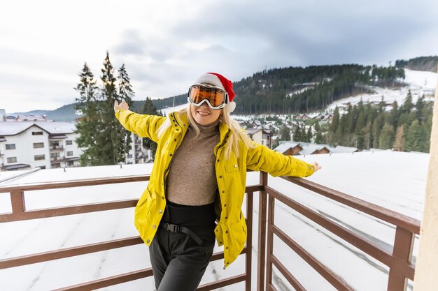 파란색 배경 위에 스키 안경과 겨울 코트를 입은 행복한 감정적인 여자.