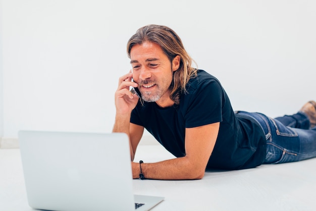 Happy employee with smartphone lying on the floor