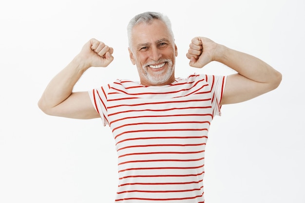 Happy enthusiastic elderly man stretching and smiling pleased