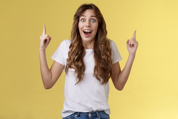 Happy enthusiastic impressed lively joyful girlfriend reacting astonished surprised excellent amusing promo gift pointing up index finger look admiration joy drop jaw fascinated temptation