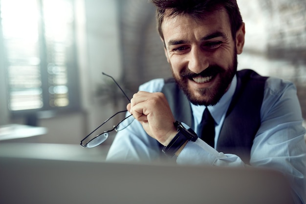 Free photo happy entrepreneur reading an email on laptop in the office