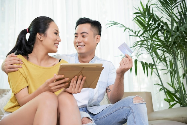 Happy ethnic couple with tablet and credit card