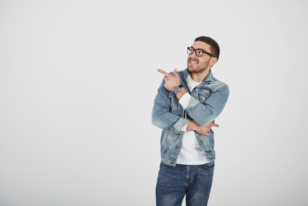 Happy excited bearded man in eyeglasses looking at camera with smile and pointing away