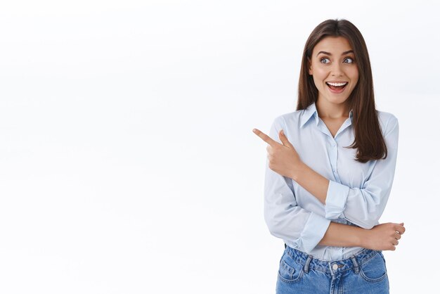 Happy excited brunette female entrepreneur impressed by how easy things can be done with this product or application smiling astonished and looking left seeing something curious white background